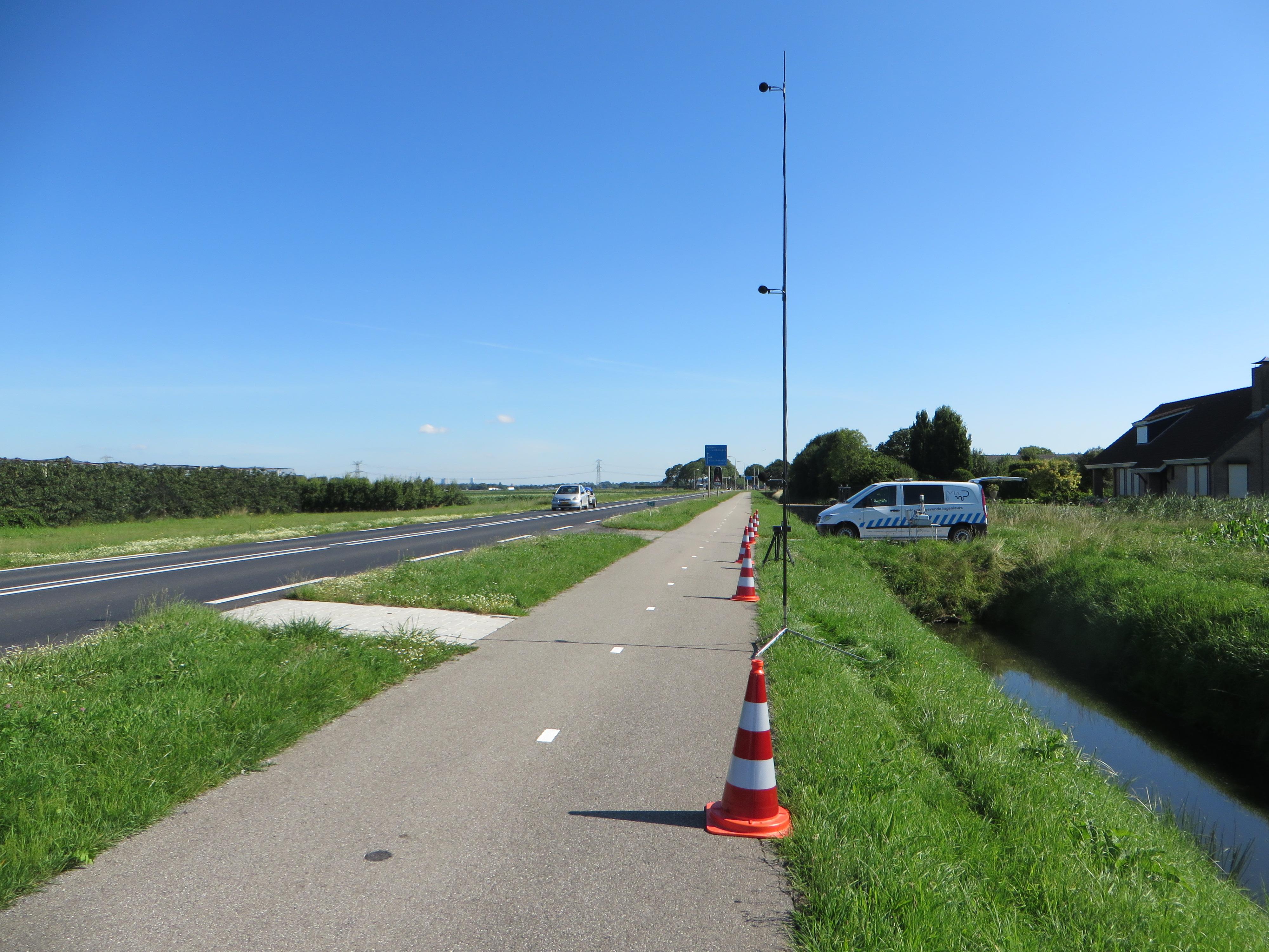 Een mast met microfoons staat langs de weg om wegdekgeluid te meten